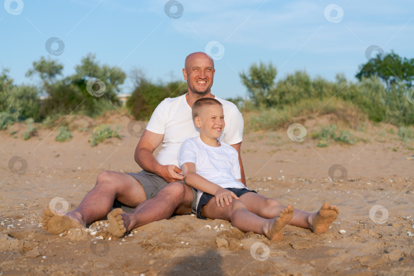 Скачать Мужчина и мальчик сидят на пляже фотосток Ozero