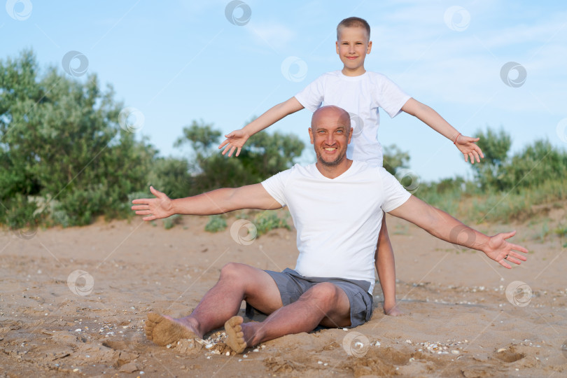 Скачать Мужчина и мальчик сидят на пляже фотосток Ozero