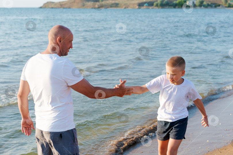 Скачать Мужчина и мальчик играют на пляже фотосток Ozero