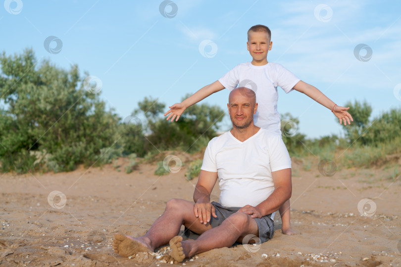 Скачать Мужчина и мальчик сидят на пляже фотосток Ozero