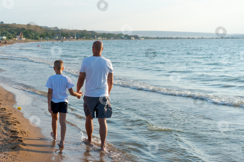 Скачать Мужчина и мальчик прогуливаются по пляжу фотосток Ozero