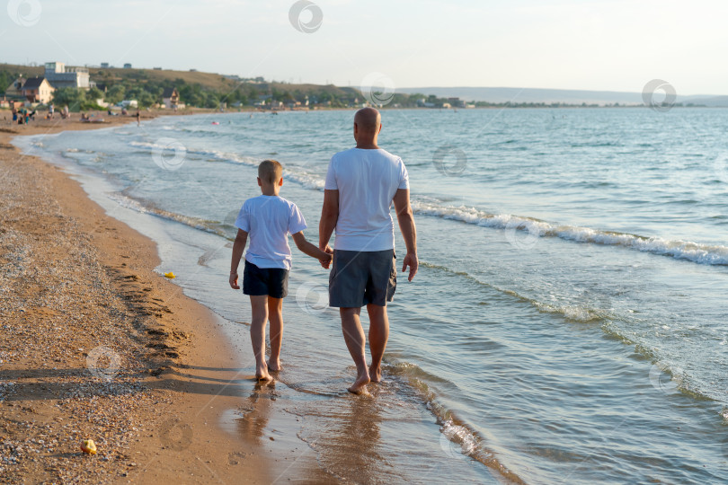 Скачать Мужчина и мальчик прогуливаются по пляжу фотосток Ozero