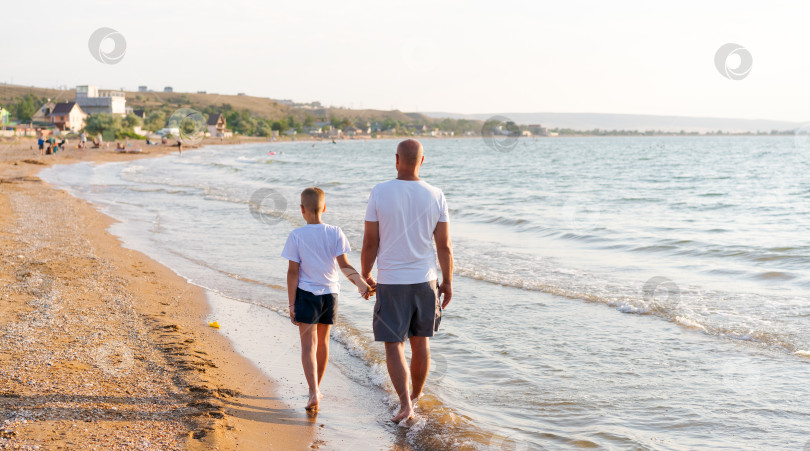 Скачать Мужчина и мальчик прогуливаются по пляжу фотосток Ozero