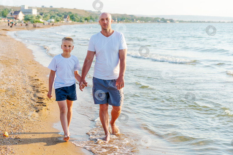 Скачать Мужчина и мальчик прогуливаются по пляжу фотосток Ozero