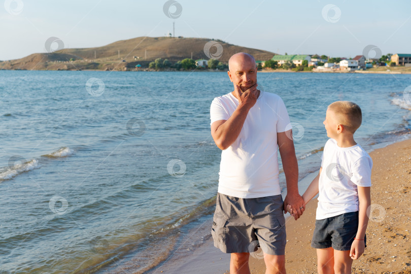 Скачать Мужчина и мальчик прогуливаются по пляжу фотосток Ozero