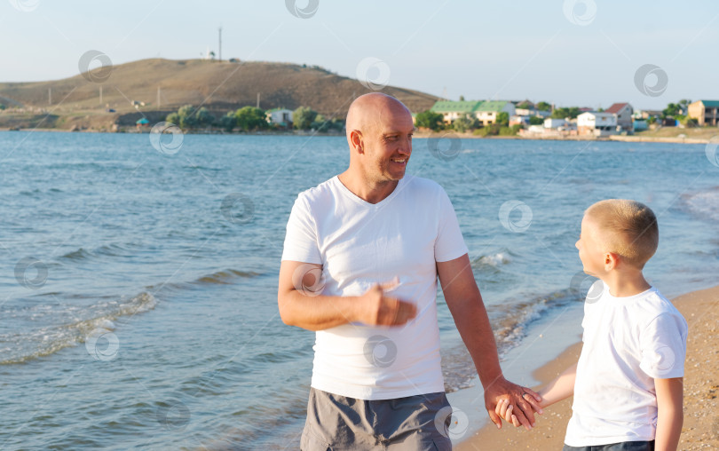Скачать Мужчина и мальчик прогуливаются по пляжу фотосток Ozero