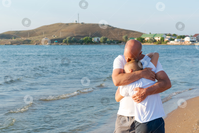 Скачать Мужчина обнимает ребенка на пляже фотосток Ozero