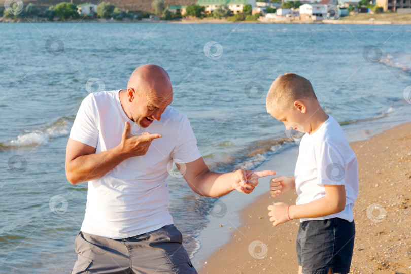 Скачать Мужчина и мальчик стоят на пляже фотосток Ozero