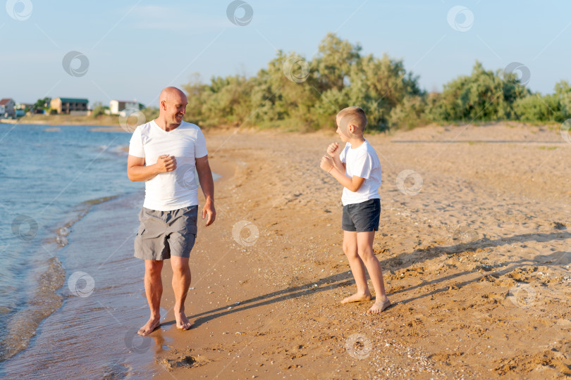 Скачать Мужчина и мальчик прогуливаются по пляжу фотосток Ozero