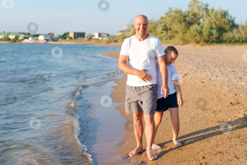 Скачать Мужчина и мальчик прогуливаются по пляжу фотосток Ozero