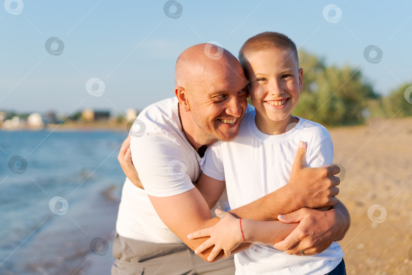 Скачать Мужчина и мальчик обнимаются на пляже фотосток Ozero