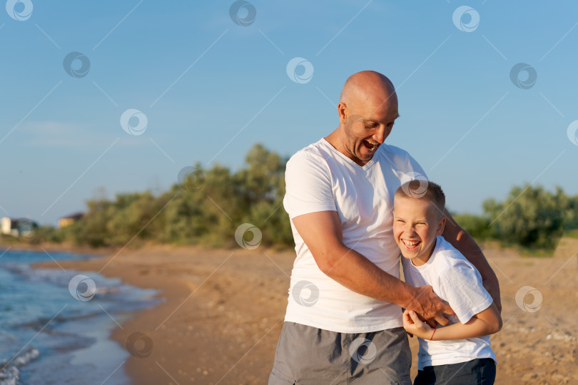 Скачать Мужчина и мальчик стоят на пляже фотосток Ozero