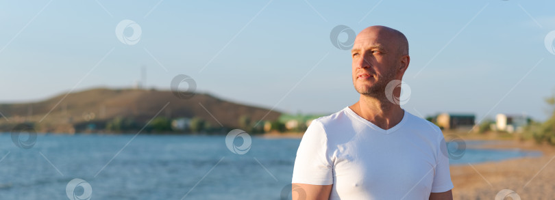 Скачать Мужчина стоит на пляже и смотрит на воду фотосток Ozero