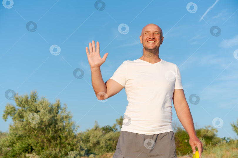 Скачать Мужчина стоит в поле с распростертыми руками и улыбкой на лице фотосток Ozero
