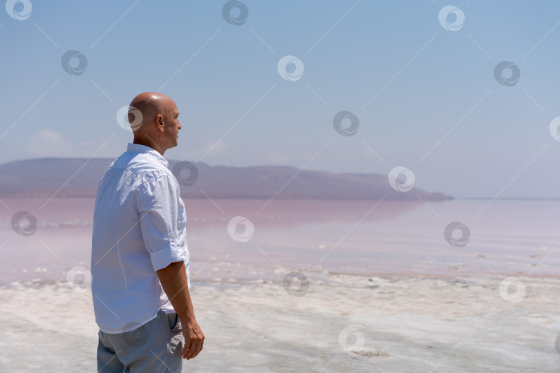 Скачать Мужчина стоит на пляже и смотрит на океан фотосток Ozero