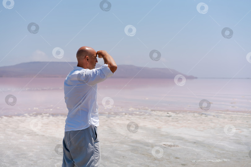 Скачать Мужчина стоит на пляже и смотрит на воду фотосток Ozero