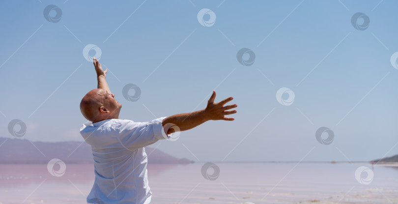 Скачать Мужчина стоит на пляже и протягивает к нему руки фотосток Ozero