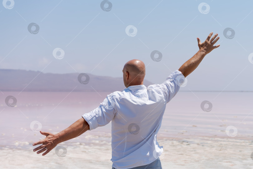 Скачать Мужчина стоит на пляже, раскинув руки фотосток Ozero