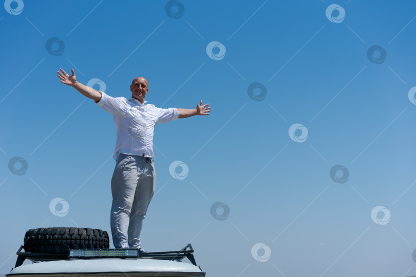 Скачать Мужчина стоит на крыше автомобиля фотосток Ozero