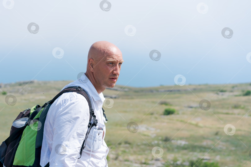 Скачать Мужчина с лысой головой одет в белую рубашку и несет рюкзак фотосток Ozero