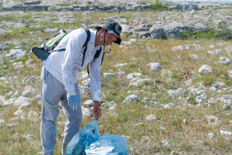 Скачать Мужчина собирает мусор в поле фотосток Ozero