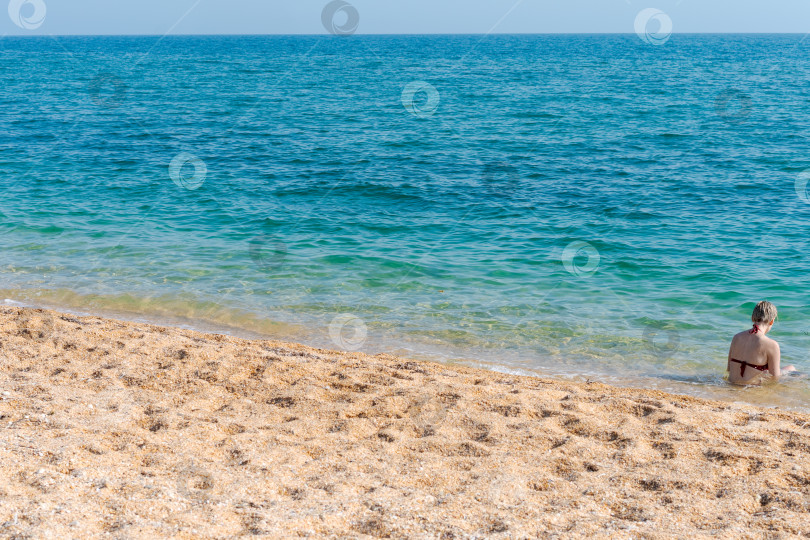 Скачать Женщина сидит в воде на пляже фотосток Ozero