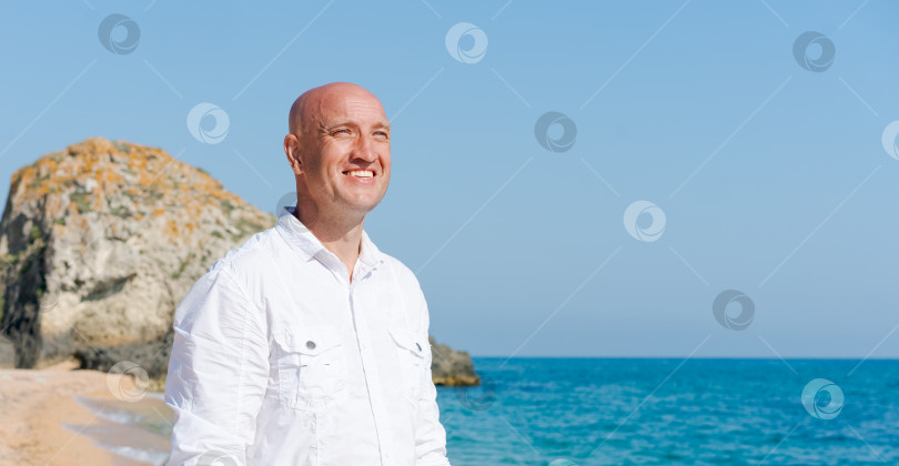 Скачать Мужчина с лысой головой стоит на пляже фотосток Ozero