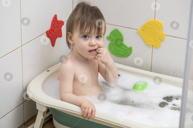 Скачать Маленькая девочка купается, сидя в детской ванночке фотосток Ozero