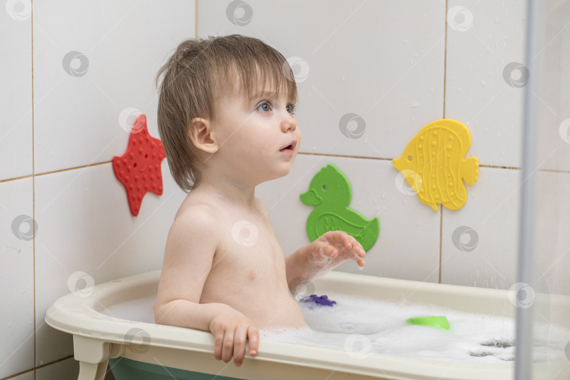 Скачать Маленькая девочка купается, сидя в детской ванночке фотосток Ozero