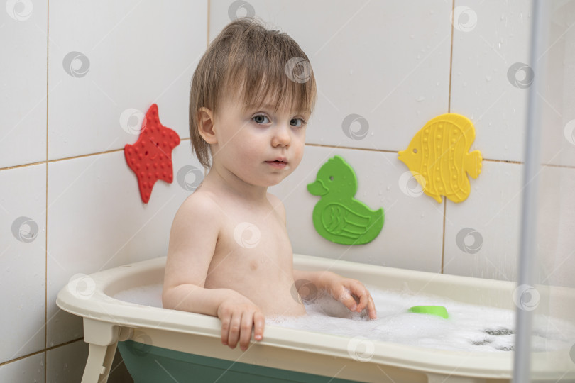 Скачать Маленькая девочка купается, сидя в детской ванночке фотосток Ozero