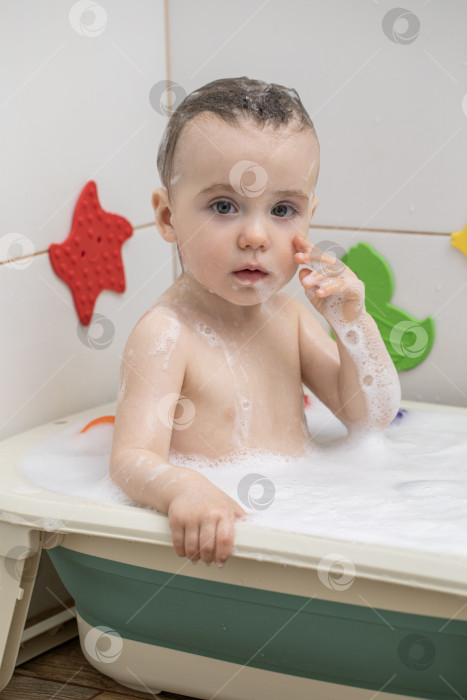 Скачать Маленькая девочка купается, сидя в детской ванночке фотосток Ozero