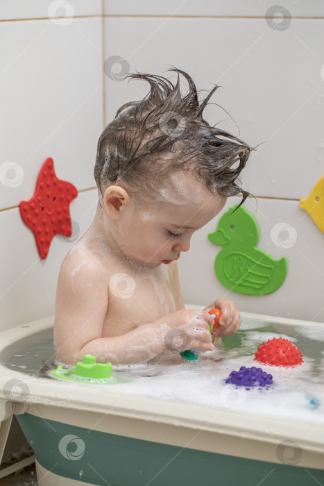 Скачать Маленькая девочка купается, сидя в детской ванночке фотосток Ozero