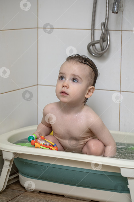 Скачать Маленькая девочка купается, сидя в детской ванночке фотосток Ozero