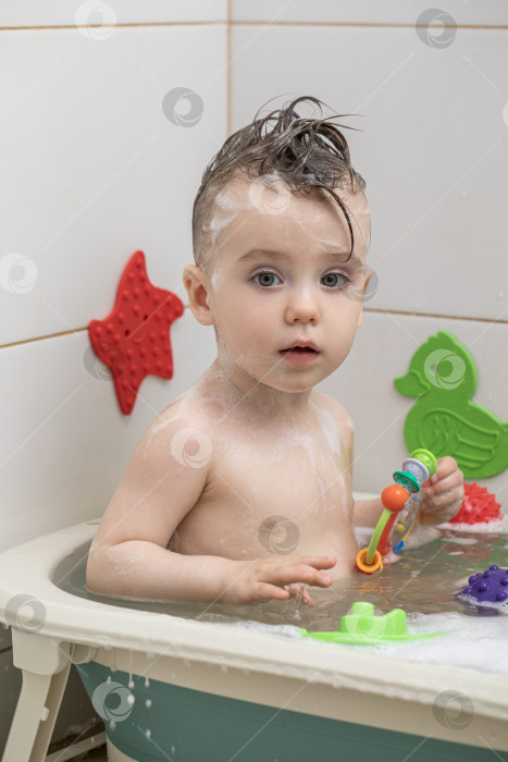 Скачать Маленькая девочка купается, сидя в детской ванночке фотосток Ozero