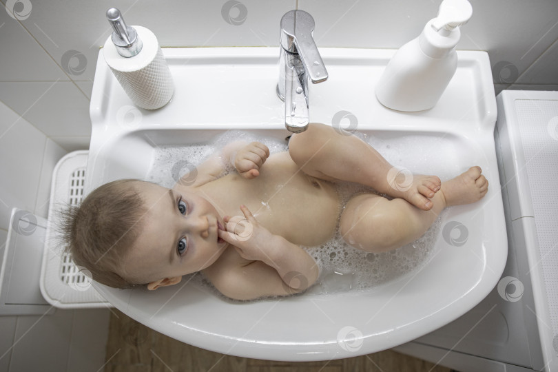 Скачать Маленькая девочка лежит в раковине в ванной фотосток Ozero