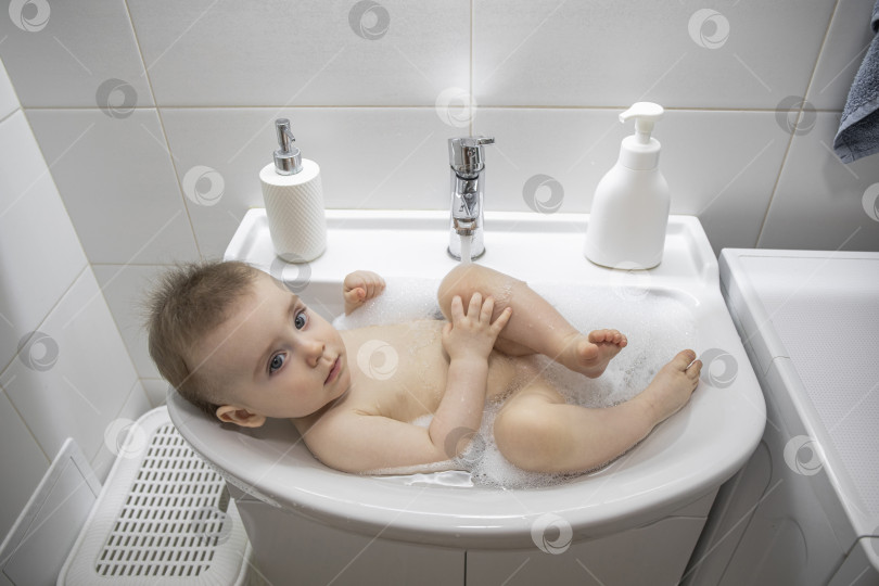 Скачать Маленькая девочка лежит в раковине в ванной фотосток Ozero