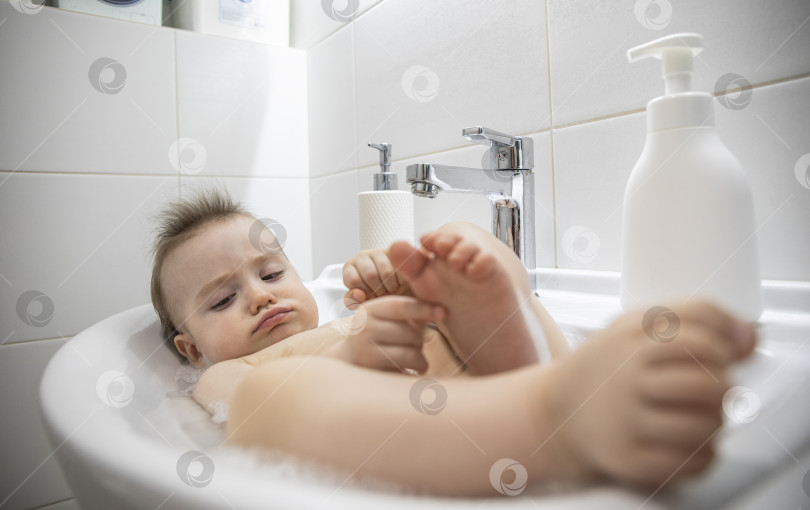 Скачать Маленькая девочка лежит в раковине в ванной фотосток Ozero
