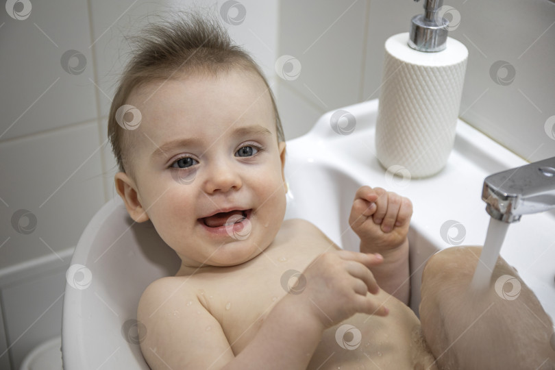 Скачать Маленькая девочка лежит в раковине в ванной фотосток Ozero