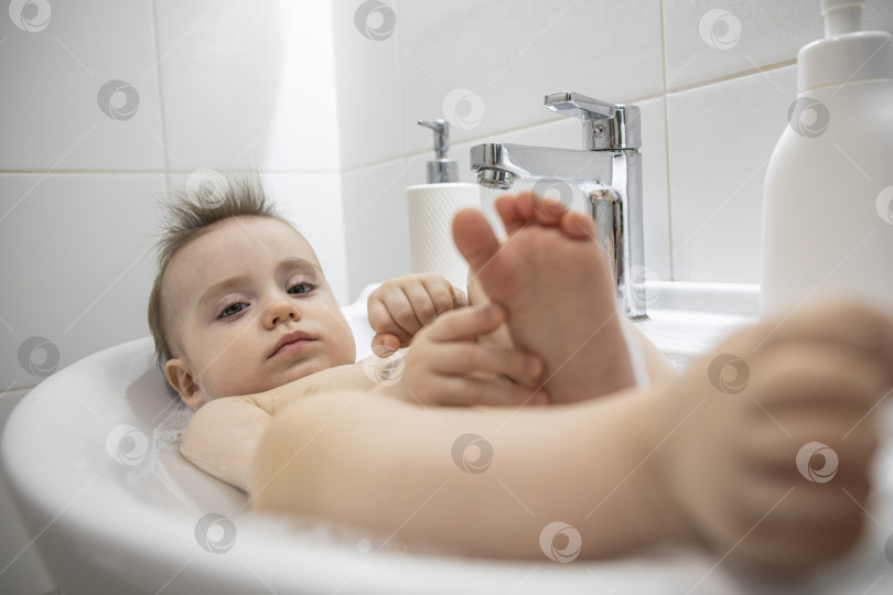 Скачать Маленькая девочка лежит в раковине в ванной фотосток Ozero