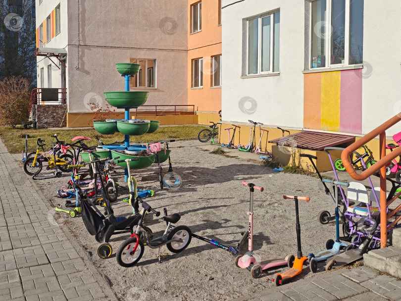 Скачать Парковка детских велосипедов и самокатов перед крыльцом у детского сада фотосток Ozero
