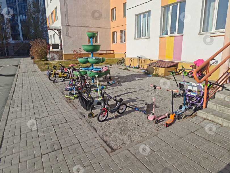 Скачать Парковка детских велосипедов и самокатов перед крыльцом у детского сада фотосток Ozero