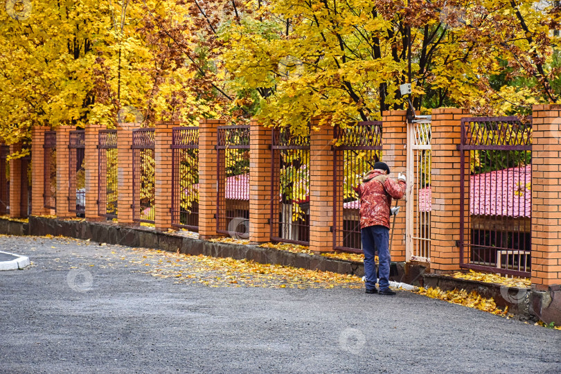 Скачать Дворник подметает осеннюю листву фотосток Ozero