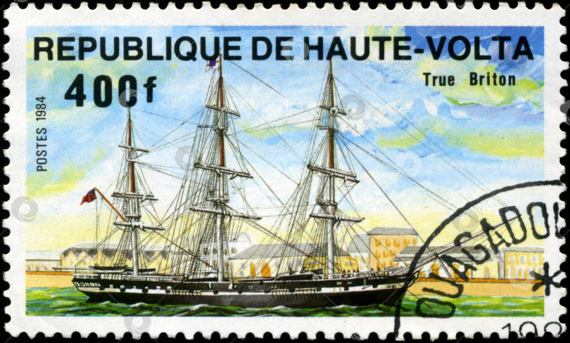 Скачать РЕСПУБЛИКА ВЕРХНЯЯ ВОЛЬТА - ОКОЛО 1984 года: На марке, напечатанной в Республике Верхняя Вольта, изображен корабль "Истинный британец", серия посвящена парусным судам, около 1984 года. фотосток Ozero