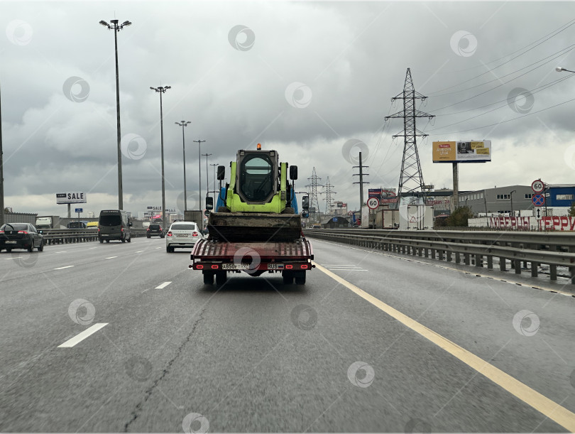 Скачать Эвакуатор перевозит мини-погрузчик по шоссе фотосток Ozero