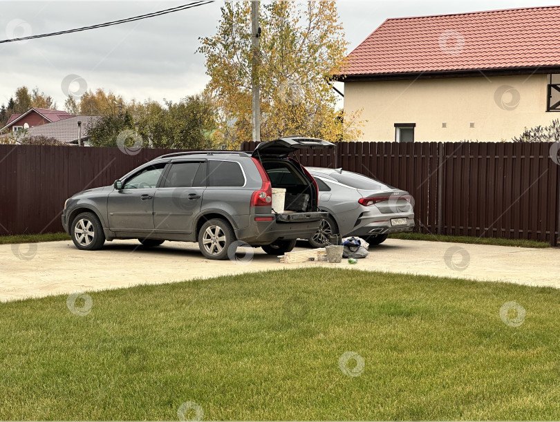 Скачать Два автомобиля припаркованы на открытой площадке у частного дома фотосток Ozero
