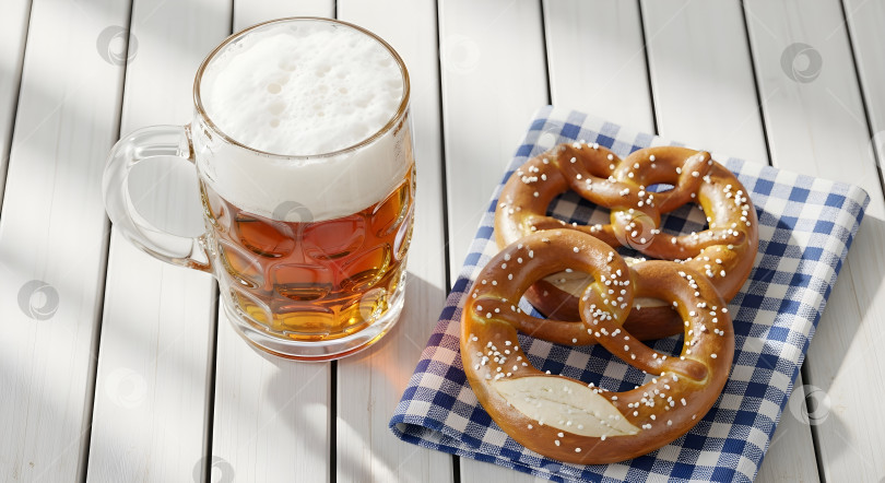 Скачать Полная кружка пива с пенкой и два соленых кренделька на клетчатой салфетке фотосток Ozero