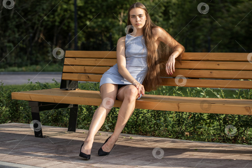 Скачать Молодая красивая женщина сидит на скамейке в летнем парке фотосток Ozero