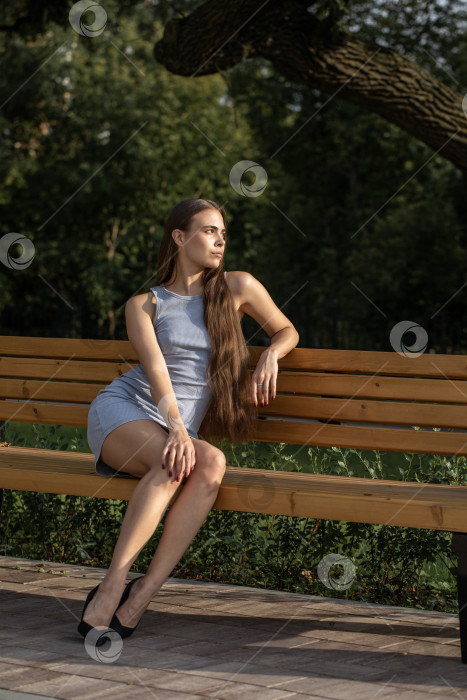 Скачать Молодая красивая женщина сидит на скамейке в летнем парке фотосток Ozero