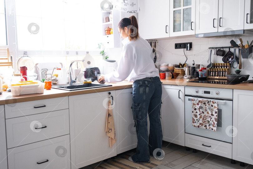 Скачать Женщина готовит и убирает на кухне фотосток Ozero