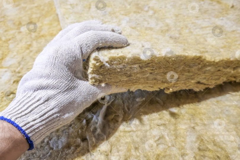 Скачать Крупным планом рука в перчатке берет лист теплоизоляционного материала. фотосток Ozero